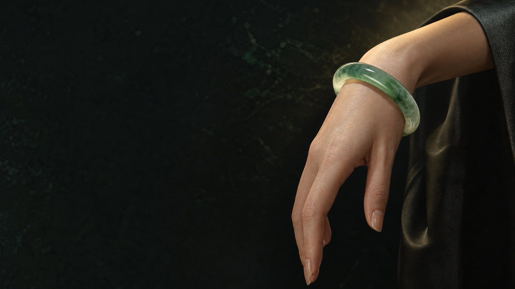 Icy green jadeite bangle on an elegant wrist against an obsidian setting